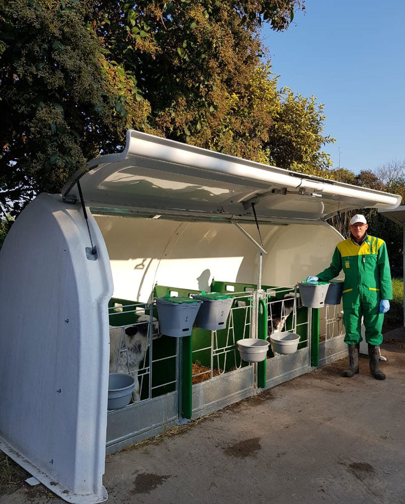 Gallery image of CalfOTel calf hutches; a worker standing next to a Hybrid Calf Hutch