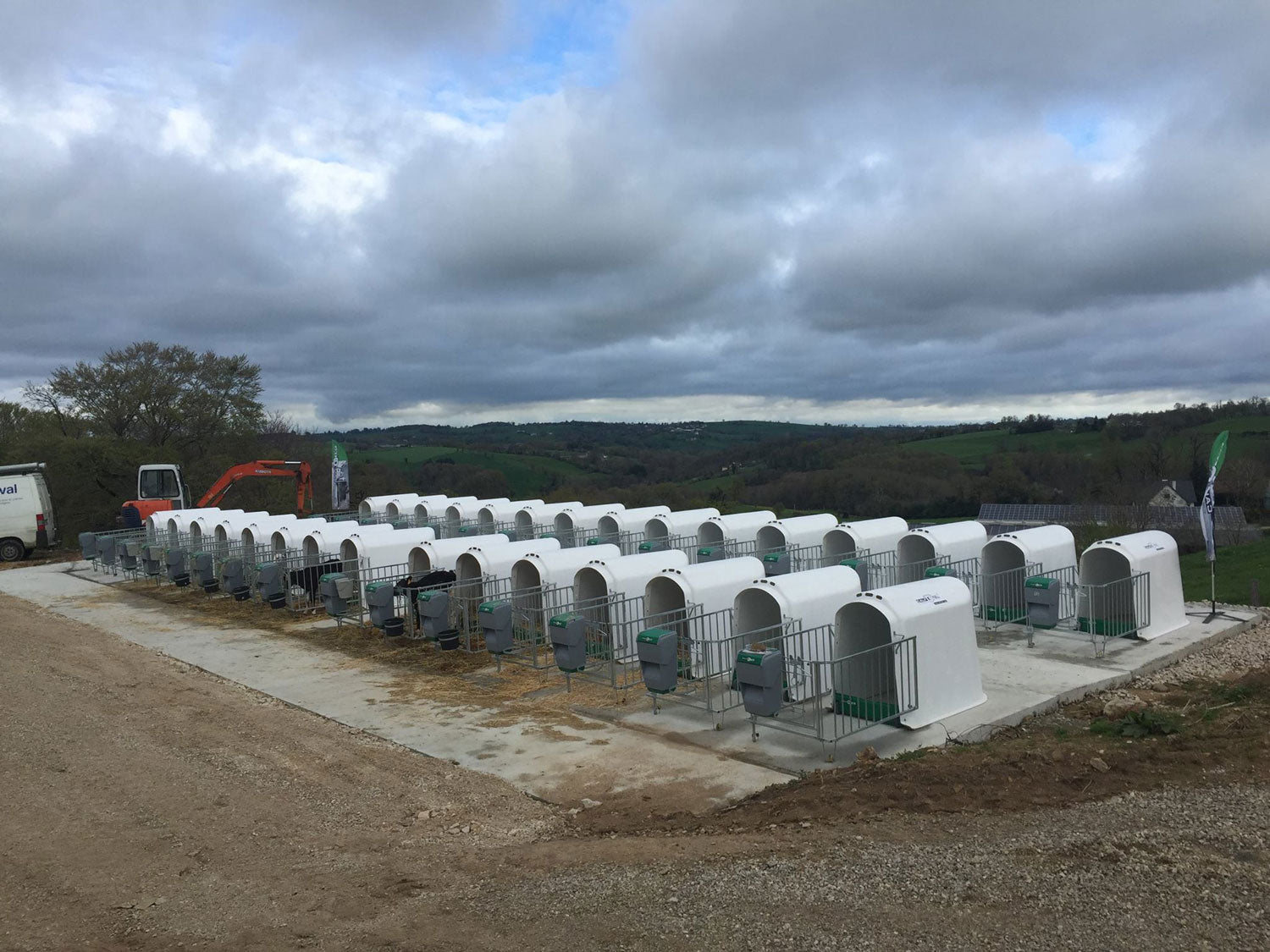 Gallery image of CalfOTel calf hutches; this is a group of Outdoor Individual hutches under a dramatic