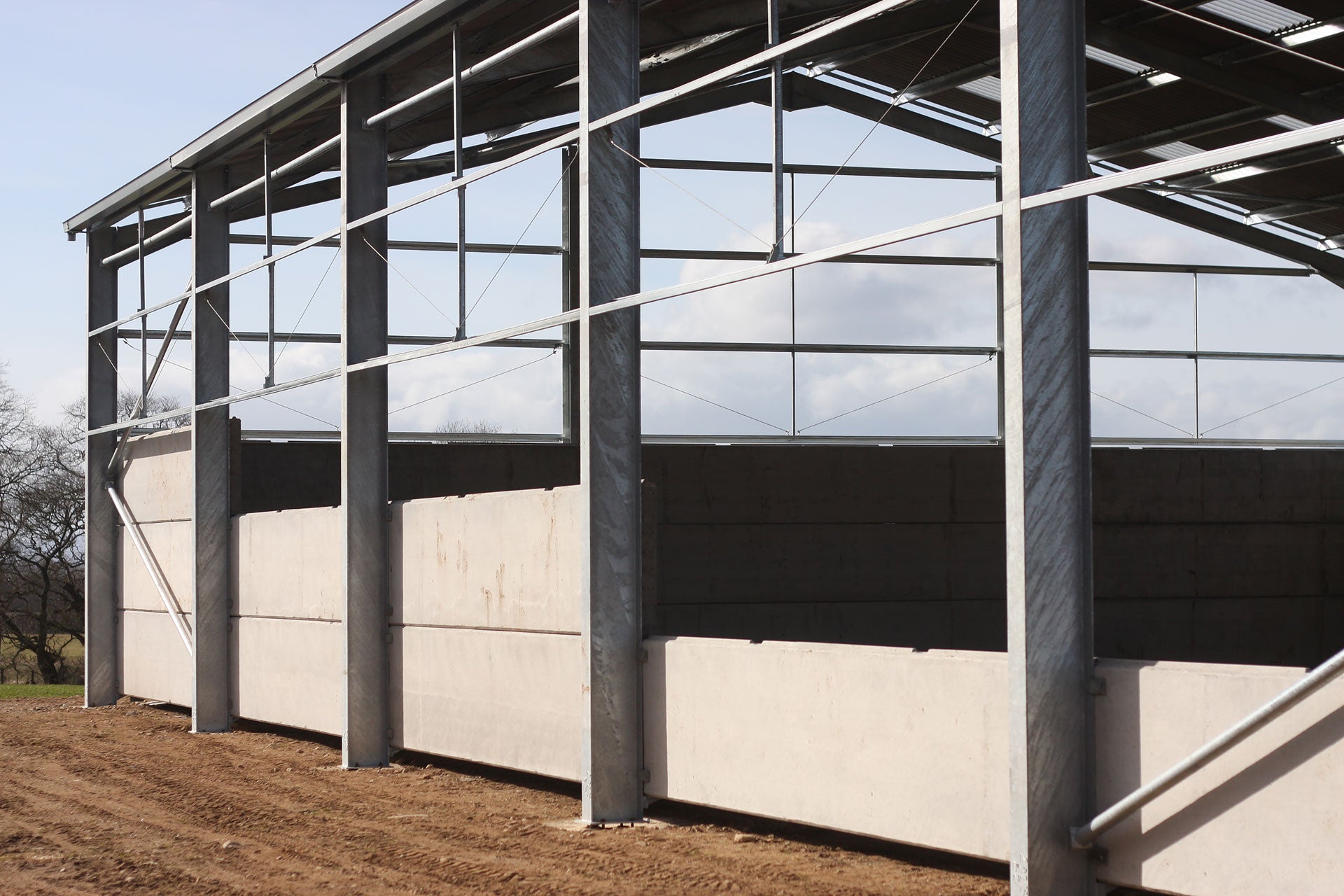 Image shows a half-completed barn, with concrete panels installed along the side